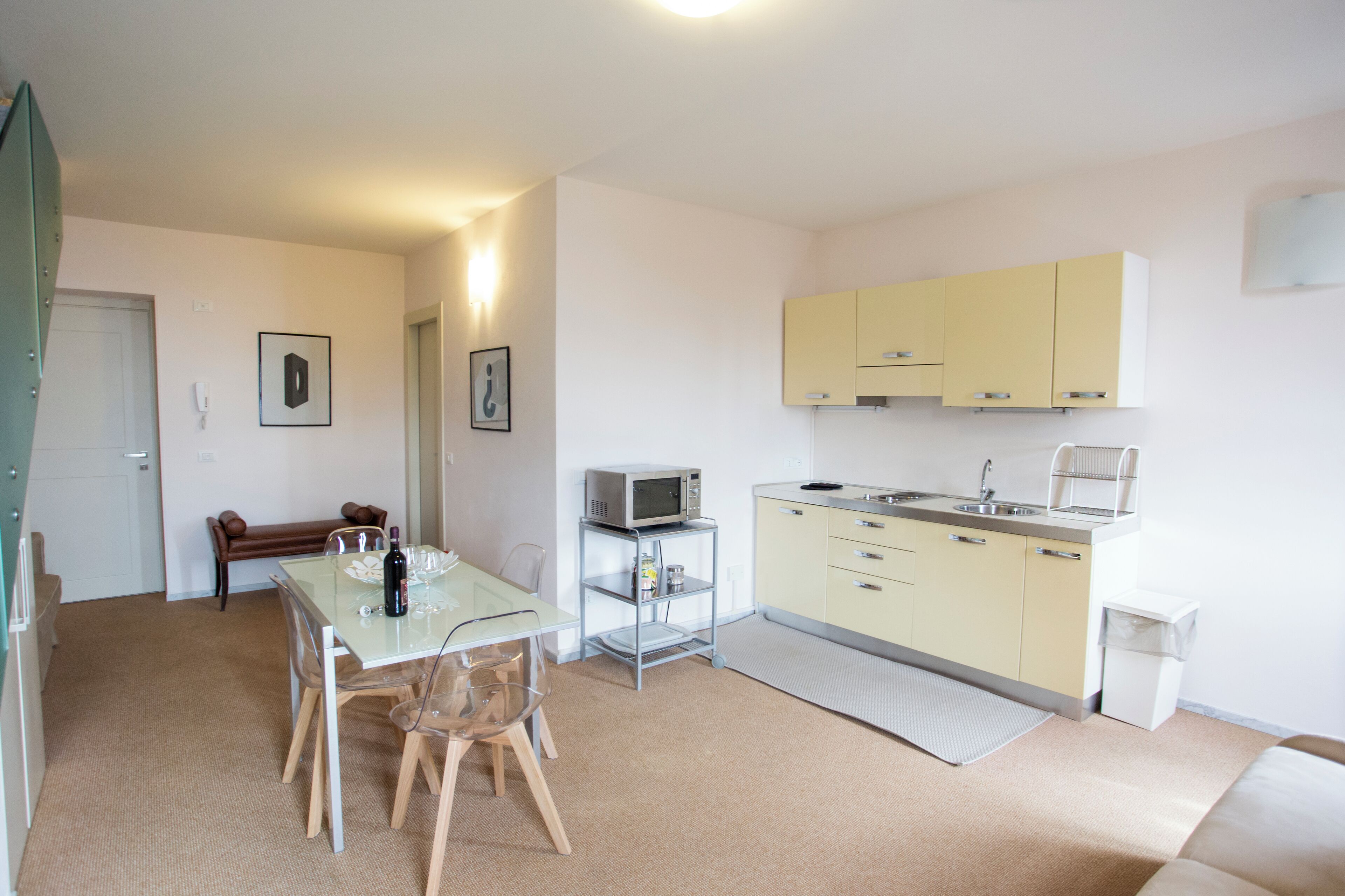 A compact kitchen with a dining area, including a microwave, sink, and a small refrigerator.