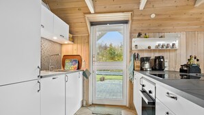 A modern kitchen with white cabinets, a large window, and a coffee station. - Cozy home in Spøttrup with WiFi (Spøttrup)