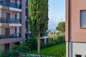 A modern apartment building with balconies, a well-maintained lawn, and a tall tree in the foreground. - Adele's House - with pool terrace and WiFi (Sirmione)