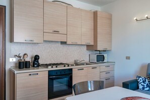 A modern kitchen with light wood cabinets, a gas stove, an oven, a microwave, and a sink. - Adele's House - with pool terrace and WiFi (Sirmione)