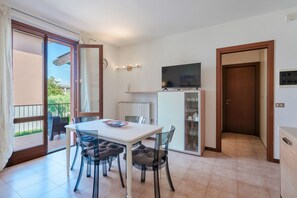 A modern apartment with a dining area, a TV, and a view of the outside. - Adele's House - with pool terrace and WiFi (Sirmione)