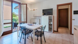 A modern apartment with a dining area, a TV, and a view of the outside. - Adele's House - with pool terrace and WiFi (Sirmione)
