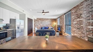 Una cocina moderna con electrodomésticos de acero inoxidable, un comedor con mesa de madera y una pared de ladrillo.