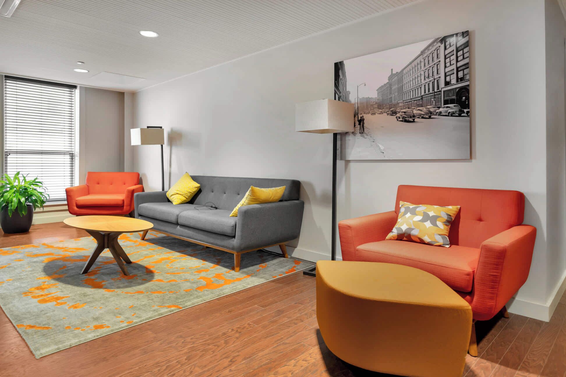 Una sala de estar moderna con un sofá gris, sillones naranjas y una mesa de centro.