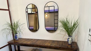 A wooden bench with a shelf underneath, flanked by two mirrors and two potted plants. - White Beach Hostel (Koh Rong)