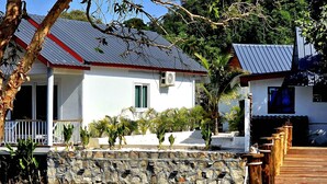 A wooden dock leading to a house with a stone wall and a metal roof. - White Beach Hostel (Koh Rong)
