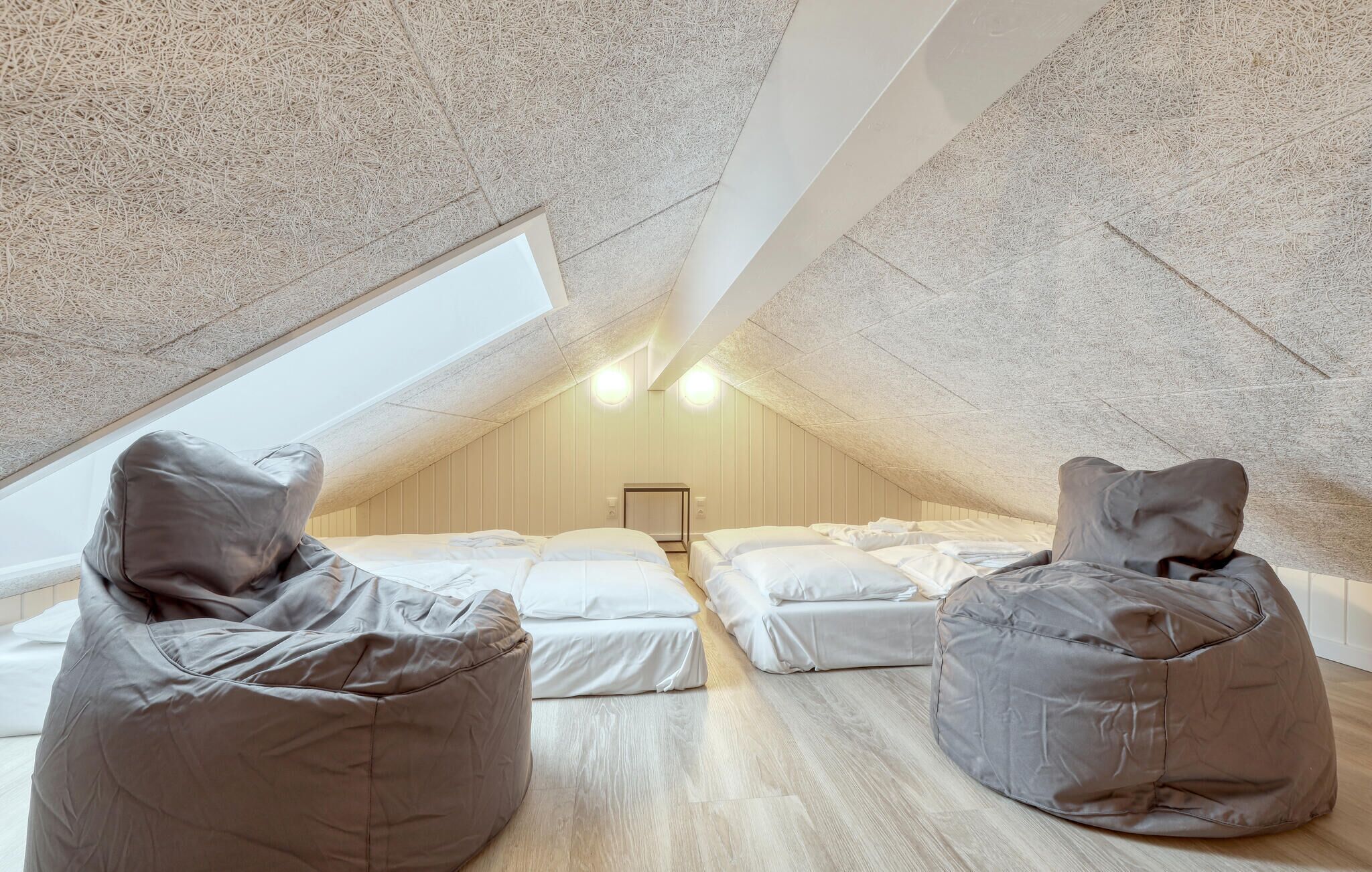Quarto de sótão aconchegante com duas camas e duas poltronas de milho, um claraboia e uma pequena mesa.
