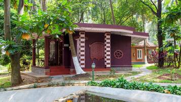 Stroll through the tranquil garden, surrounded by lush greenery and a traditional red-brick building with a distinctive checkered pattern.