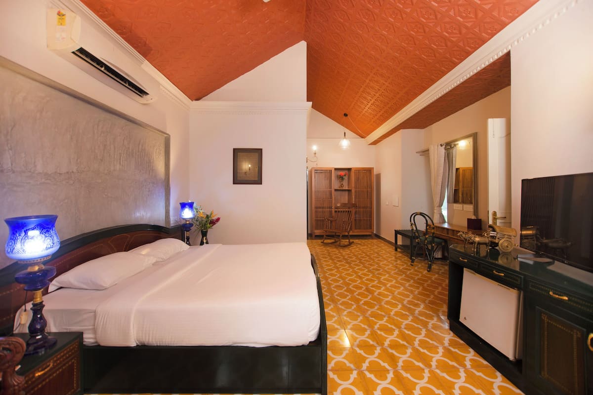 A hotel room with a bed, bedside table, lamp, and a mirror.