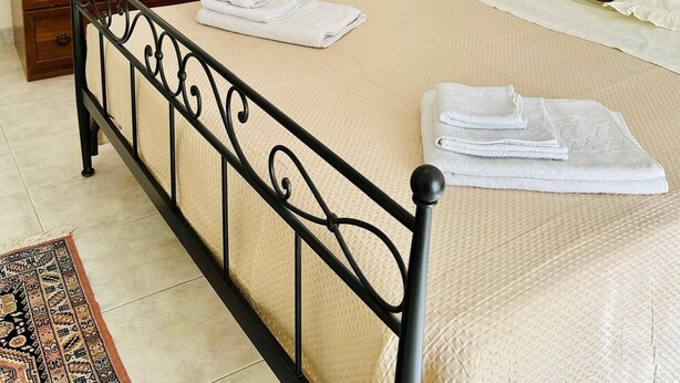 A neatly arranged bedroom with a bed, a wooden dresser, a nightstand, and a bedside table. - Ti Aspettiamo nel Nostro Luminoso Appartamento (Gela)