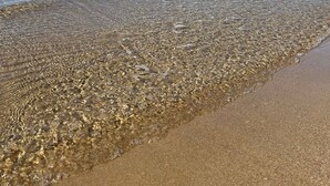 A clear beach with calm waters, a rocky breakwater, and a distant pier. - Ti Aspettiamo nel Nostro Luminoso Appartamento (Gela)
