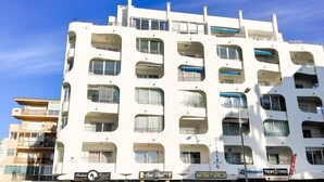 Een meerlaags gebouw met balkons, etalages en een geparkeerde auto.