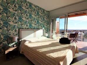 Une chambre Ă coucher avec un lit, une table de chevet, une lampe et une vue sur lâextĂ©rieur.