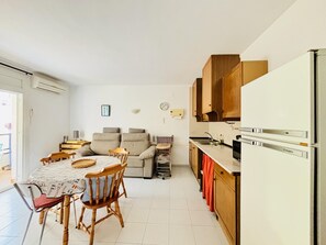 Un espacio habitable compacto con comedor, sofá, kitchenette y una pequeña mesa.