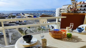 Una mesa en el balcón con vistas al puerto deportivo y al paisaje urbano.