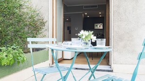 A patio with a table and chairs, a small garden area, and a glimpse of the interior through an open door. - Easylife -Modern apartment with Patio C.Sforzesco (Milano)