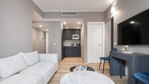 A modern living room with a sofa, a round coffee table, and a kitchen in the background. - Easylife -Modern apartment with Patio C.Sforzesco (Milano)