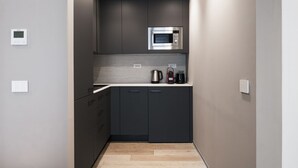 A compact kitchen with dark cabinetry, a stainless steel microwave, and a coffee maker on the countertop. - Easylife -Modern apartment with Patio C.Sforzesco (Milano)