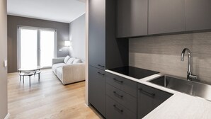 A modern kitchen with dark cabinets, a stainless steel sink, and a light-colored countertop. - Easylife -Modern apartment with Patio C.Sforzesco (Milano)