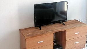 A wooden desk with a flat-screen TV, two drawers, and a power outlet. - Charming Apt in Heart of Santa Margarida, Near Beach, Terrace, & Parking (Roses)
