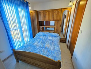 A bedroom with a bed, wooden wardrobe, and a mirror. - Sunny 2BR Apartment with Terrace & A/C, Near Beach & Nature Park, Ideal for Hiking/Biking/Windsurfing (Roses)