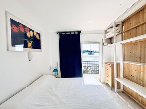 Une chambre à coucher avec un lit, un tableau, une lampe, une armoire et une vue sur l’extérieur.