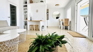 Ein modernes Wohnzimmer mit einem weißen Sofa, einem runden Couchtisch und einer großen Topfpflanze.
