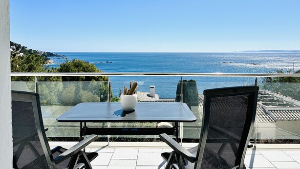 Ein Balkon mit Tisch und Stühlen mit Blick auf die Küste.