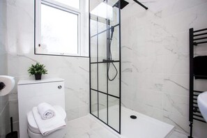 A modern bathroom with a glass-enclosed shower, a toilet, and a sink. - Vacant Nests - The Ocean Retreat (South Tyneside)