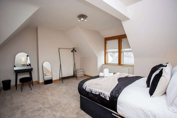 Une chambre à coucher avec un lit, un bureau, un miroir, un radiateur et une fenêtre.