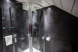 A glass-enclosed shower with a handheld showerhead, a glass shelf, and a towel rack. - Vacant Nests - The Ocean Retreat (South Tyneside)