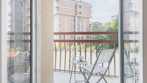 A balcony with a metal railing, a folding chair, and a small table with a cup and a book. - Easylife - Modern studio in the heart of Navigli (Milano)