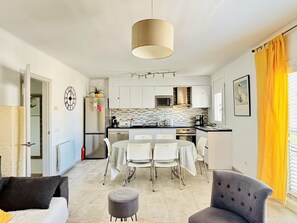 A modern kitchen with white cabinets, a dining area with a table and chairs, and a large pendant light.