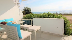 A balcony with a table set for breakfast, a chair, and a view of the sea. - Cozy studio with terrace and included parking (Roses)