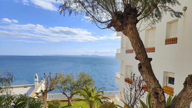 Um edifício costeiro com uma escadaria que leva a uma varanda com vista para o mar.