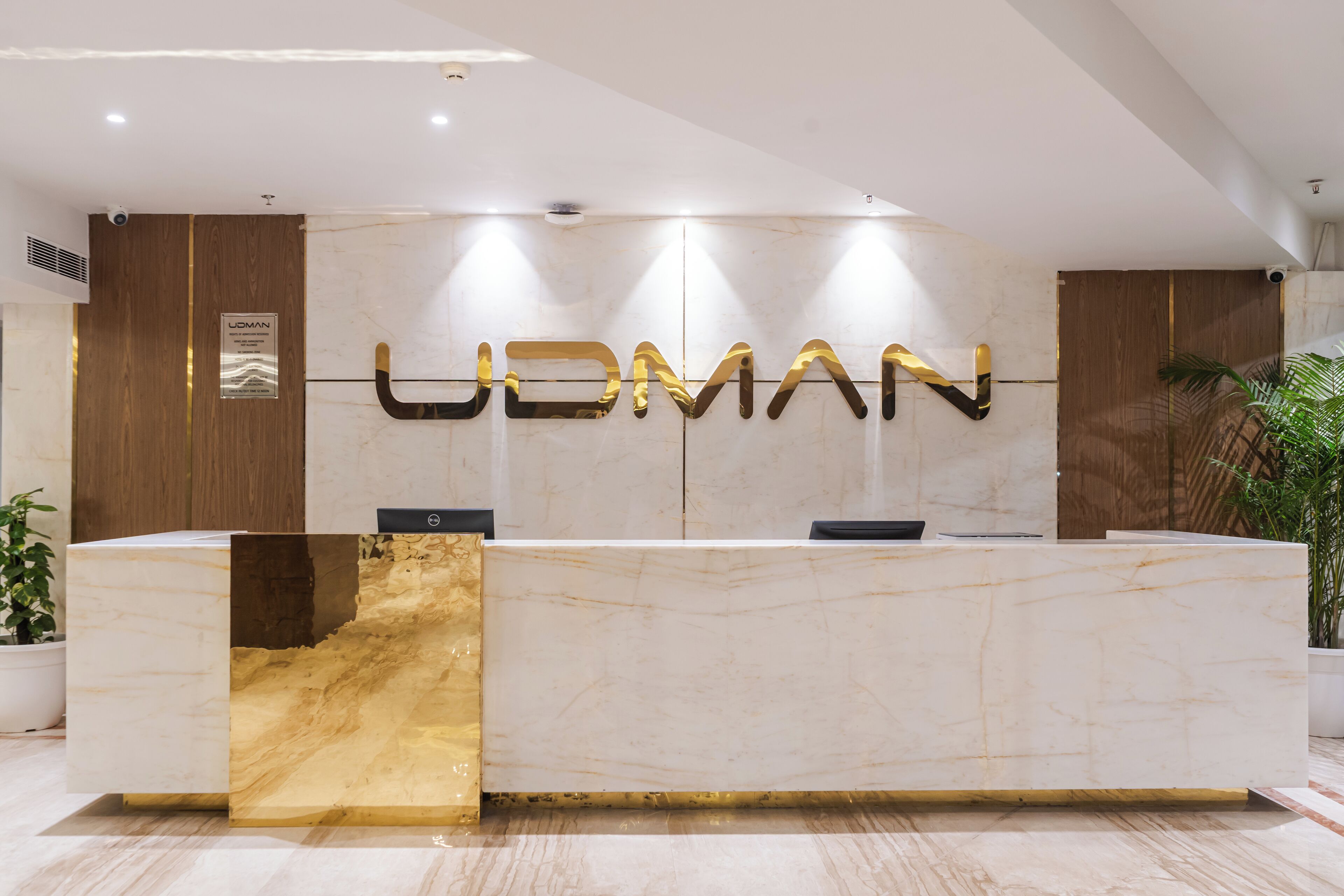 A reception desk with a marble top and a gold accent. The name "UDMAN" is prominently displayed above the desk.