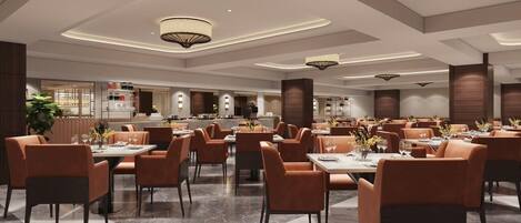 A spacious dining area with multiple tables and chairs, a kitchen in the background, and modern lighting fixtures.