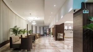 Un hall d’hôtel avec un sol en marbre, un espace détente avec des canapés, des plantes en pot et un comptoir d’accueil.
