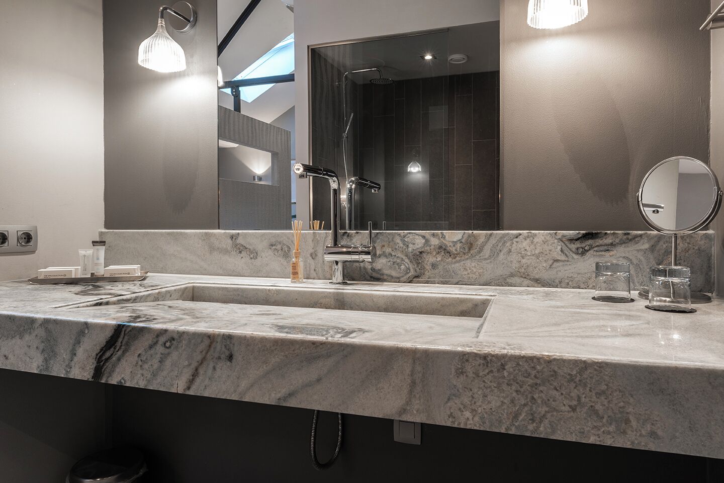 A modern bathroom with a large mirror, two sinks, and a shower.