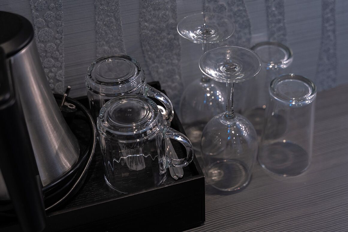 Een set glazen servies, waaronder een theepot, een karaf en wijnglazen, op een zwarte dienblad.