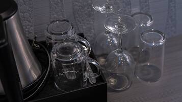 Een set glazen servies, waaronder een theepot, een karaf en wijnglazen, op een zwarte dienblad.