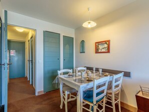 Een eetruimte met een ronde tafel, witte stoelen en een plafondlamp.