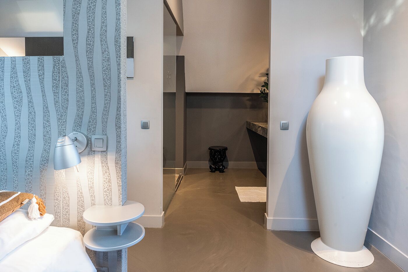 A modern bathroom with a large mirror, a round sink, and a tall vase.
