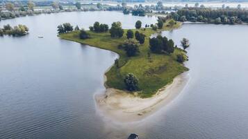 An aerial view of a lakeside property with a sandy beach, grassy areas, and scattered trees.