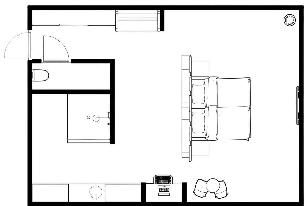 A floor plan of a hotel room with a bed, a desk, a chair, a small table, and a sink.