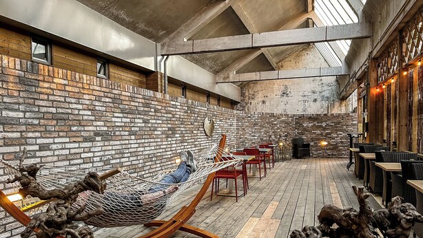A rustic interior with exposed brick walls, wooden floors, and a hammock. - Enjoy an elegant apartment with air conditioning, fast Wi-Fi, heated floors, and convenient parking—just a 5-minute walk from the Jan Cunen Museum. (Oss)