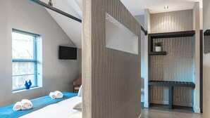 A modern hotel room with a large bed, a TV, a small window, and a plant on a shelf. - Enjoy an elegant apartment with air conditioning, fast Wi-Fi, heated floors, and convenient parking—just a 5-minute walk from the Jan Cunen Museum. (Oss)