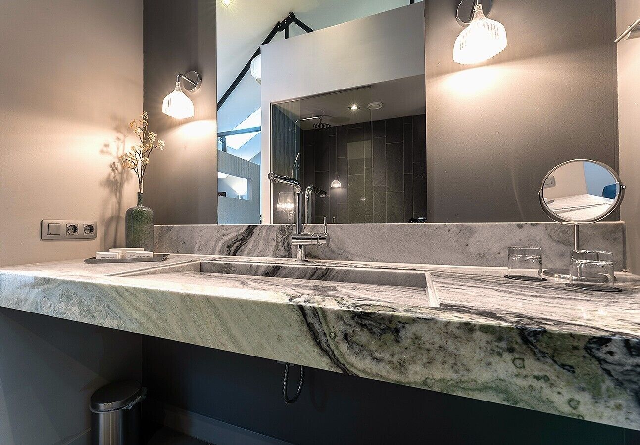 Une salle de bain moderne avec un comptoir en marbre, deux vasques et un grand miroir.