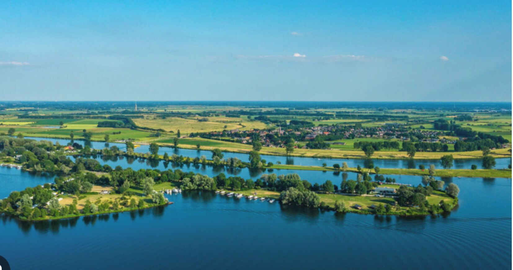 A river meandering through a rural landscape with small islands and a distant town.