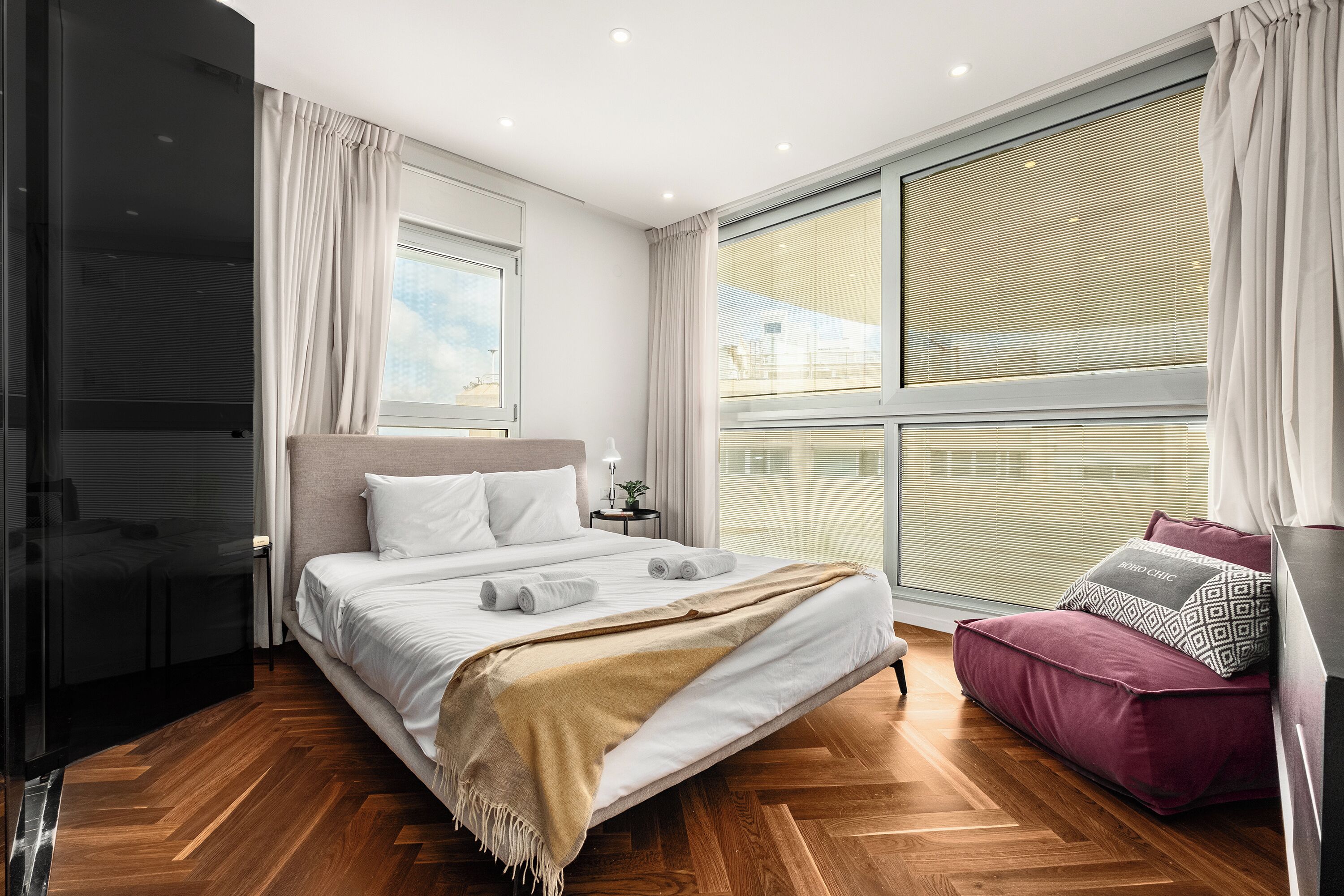 A modern bedroom with a large bed, a sofa, and a TV.